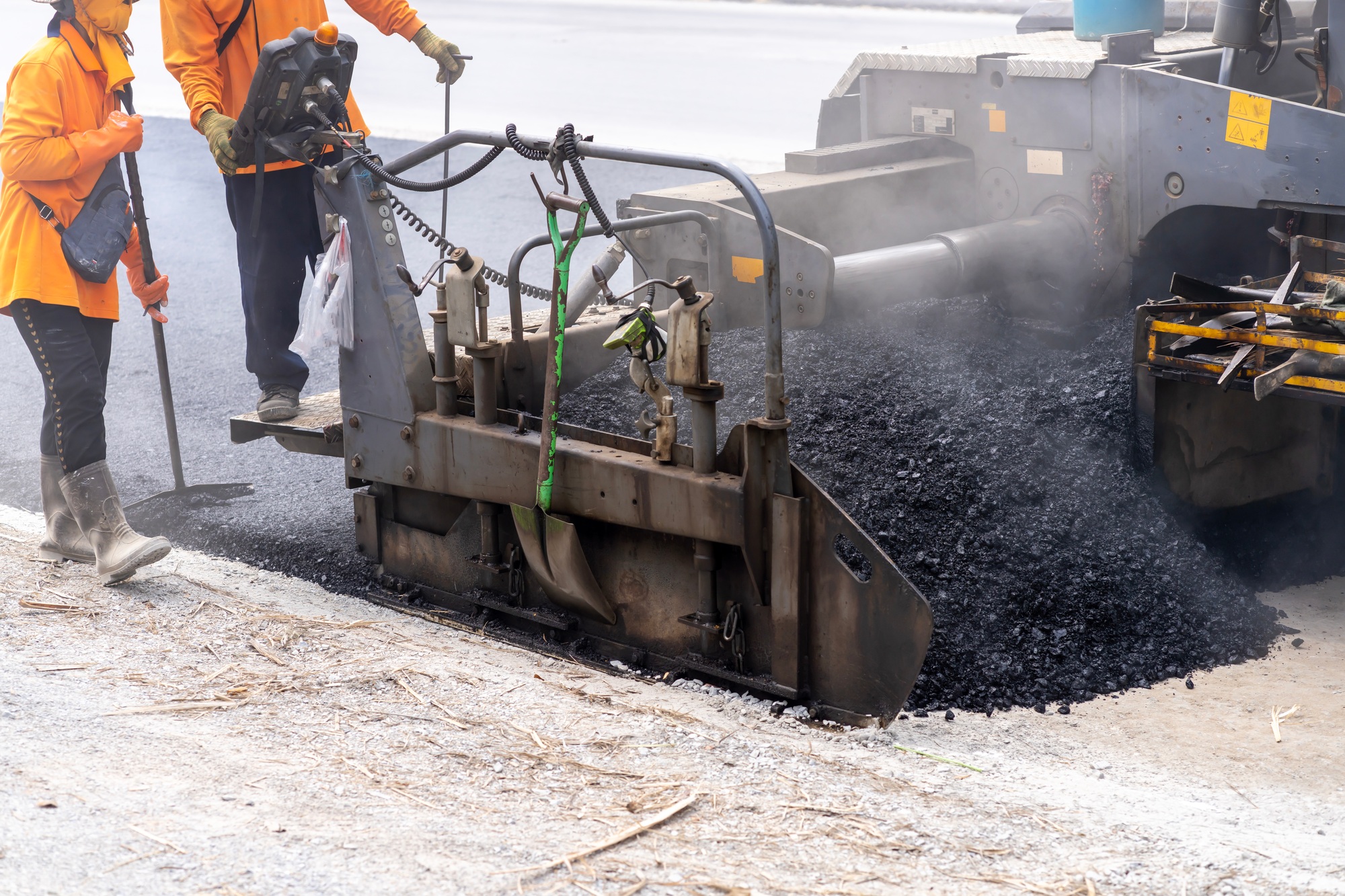 Machines are pouring asphalt to build roads for cars.