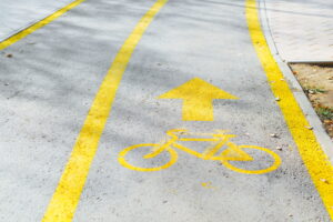 Outdoor bike path. Close-up of painted yellow bicycle sign and an arrow on pavement with stripes